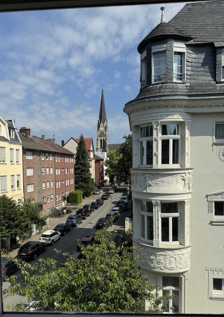 Gründerzeithaus mit Erker und Kirchturm im Hintergrund
